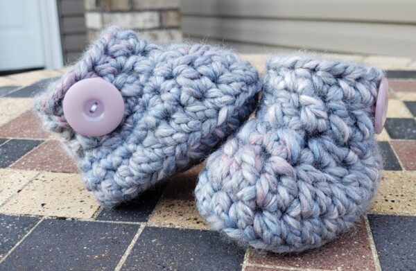 Product image of Grey baby booties with flecks of pink, purple, and blue and light lilac buttons 6-12 months old